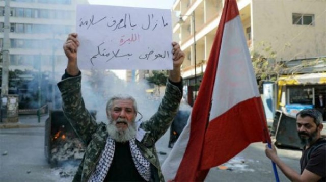 لبناني يرفع لافتة تعبر عن أزمة بلاده