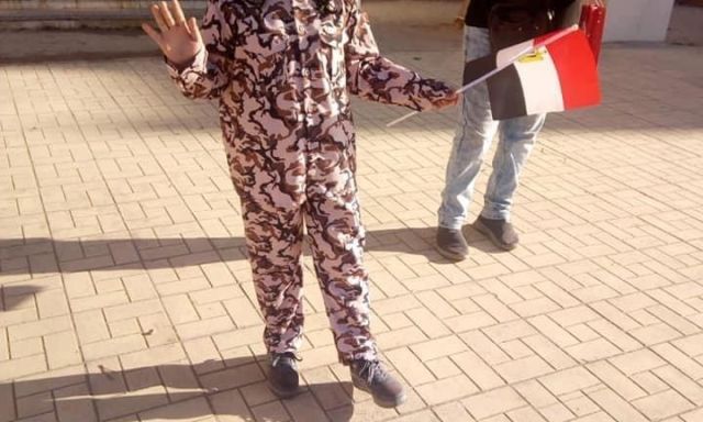 احد الطالبات اثناء تحية العلم بالزي العسكري
